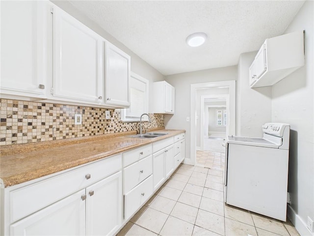 3904 Bales Ave, Kansas City, MO 64130 - kitchen with range, decorative backsplash, white cabinetry, washer / dryer, and a textured ceiling