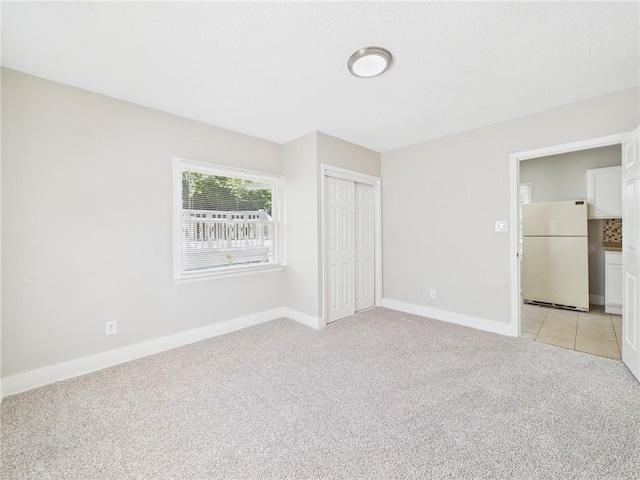 3904 Bales Ave, Kansas City, MO 64130 - unfurnished bedroom with freestanding refrigerator, light colored carpet, and a closet
