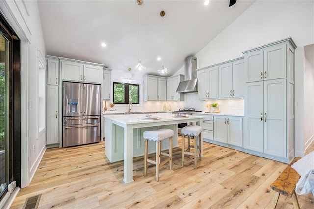 48 M St, Lake Lotawana, MO 64086 - kitchen with high end fridge, wall chimney range hood, vaulted ceiling, light countertops, and tasteful backsplash