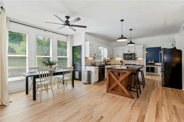 11245 S Penrose St, Olathe, KS 66061 - kitchen featuring black appliances, ceiling fan, dark countertops, decorative backsplash, and light wood-style flooring