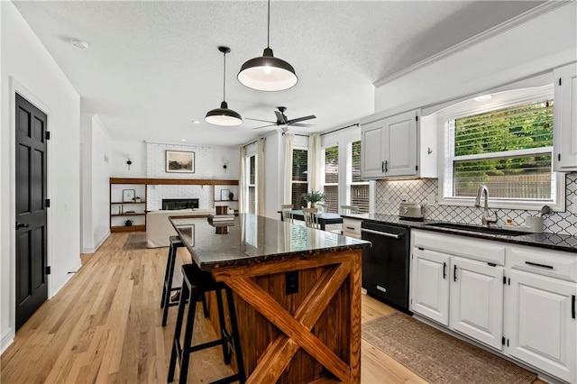 11245 S Penrose St, Olathe, KS 66061 - kitchen featuring dishwasher, a ceiling fan, decorative backsplash, light wood-style flooring, and a brick fireplace