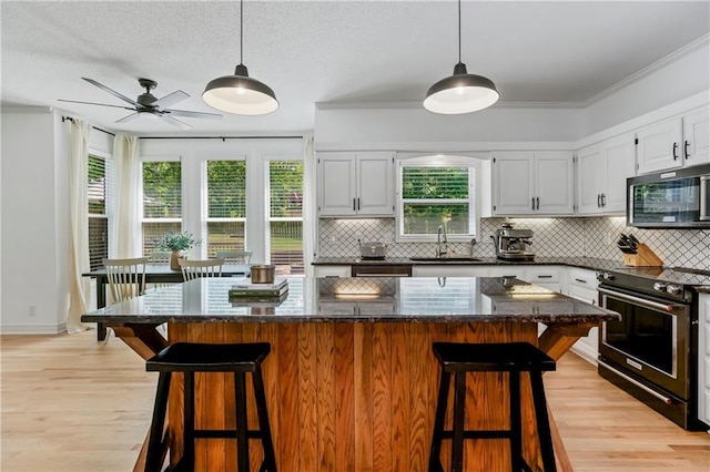 11245 S Penrose St, Olathe, KS 66061 - kitchen featuring appliances with stainless steel finishes, tasteful backsplash, light wood-style flooring, white cabinetry, and plenty of natural light