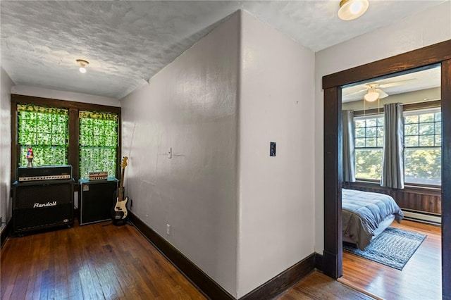 309 E Miami St, Paola, KS 66071 - hallway with wood-type flooring, a baseboard heating unit, and a textured ceiling
