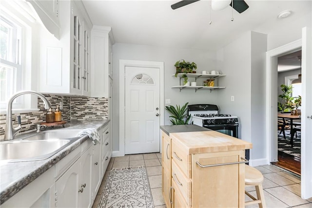 521 Tracy Ave, Kansas City, MO 64016 - kitchen with gas range, light tile patterned flooring, ceiling fan, and tasteful backsplash