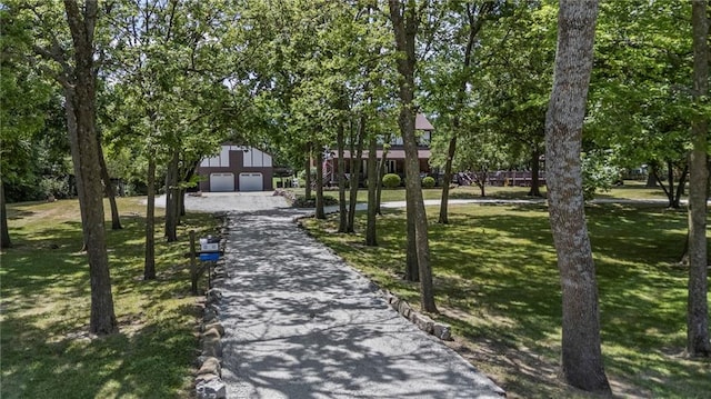 1124 S Locust St, Ottawa, KS 66067 - view of home's community featuring a yard, a garage, driveway, view of wooded area, and an outdoor structure