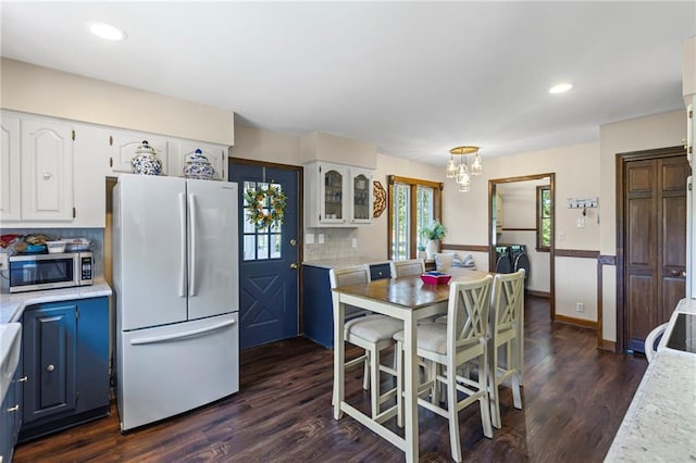 1124 S Locust St, Ottawa, KS 66067 - kitchen with freestanding refrigerator, stainless steel microwave, white cabinets, light countertops, and decorative backsplash