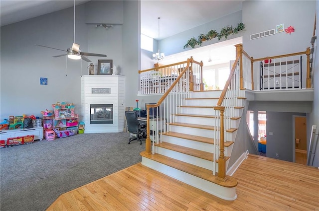 3945 N 123rd Ter, Kansas City, KS 66109 - stairs featuring a high ceiling, a glass covered fireplace, wood finished floors, a chandelier, and a ceiling fan