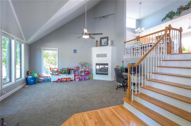 3945 N 123rd Ter, Kansas City, KS 66109 - recreation room featuring a glass covered fireplace, high vaulted ceiling, wood finished floors, ceiling fan, and a chandelier