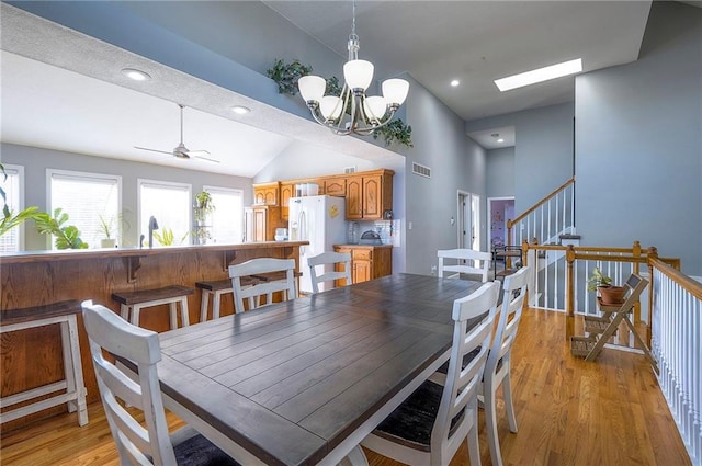 3945 N 123rd Ter, Kansas City, KS 66109 - dining room with light wood-style floors, a chandelier, high vaulted ceiling, stairway, and a ceiling fan
