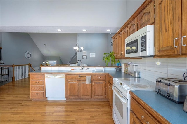 3945 N 123rd Ter, Kansas City, KS 66109 - kitchen with white appliances, a peninsula, brown cabinets, light wood-type flooring, and lofted ceiling