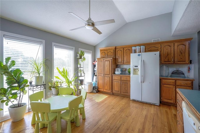3945 N 123rd Ter, Kansas City, KS 66109 - kitchen featuring white appliances, a ceiling fan, brown cabinetry, lofted ceiling, and light wood-type flooring