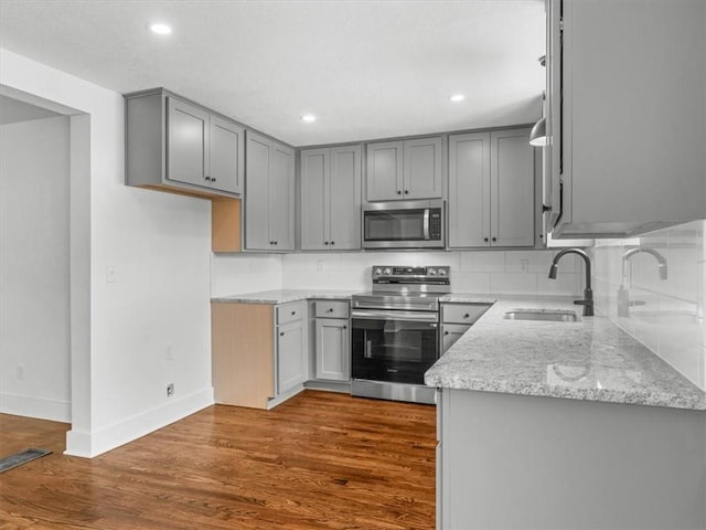 2832 Rushmore Ln, Saint Joseph, MO 64505 - kitchen featuring stainless steel appliances, gray cabinetry, light stone counters, dark wood finished floors, and recessed lighting