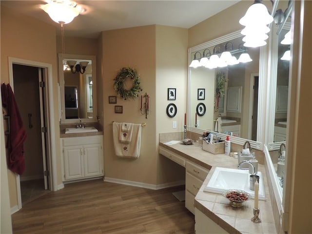 3722 S Bolger Ct, Independence, MO 64055 - bathroom featuring wood finished floors, two vanities, and a chandelier