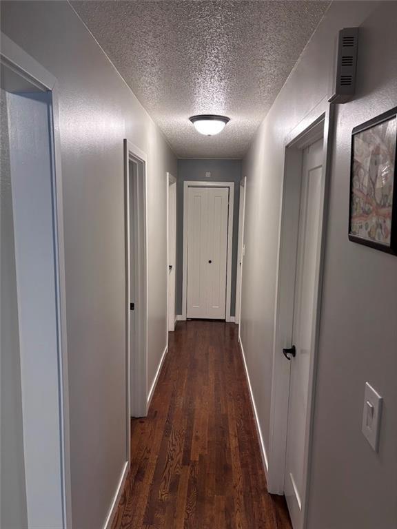 3335 N 54th St, Kansas City, KS 66104 - corridor with a textured ceiling and dark wood-style flooring