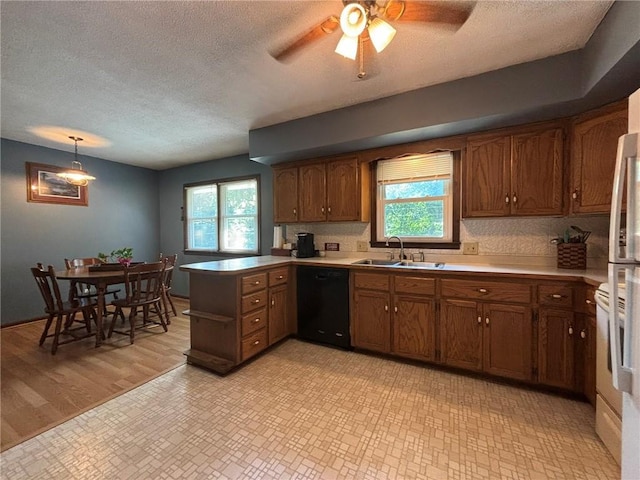 2425 Elephant Trl, Saint Joseph, MO 64506 - kitchen featuring black dishwasher, a peninsula, a textured ceiling, plenty of natural light, and brown cabinetry
