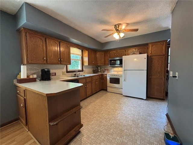 2425 Elephant Trl, Saint Joseph, MO 64506 - kitchen with white appliances, a peninsula, a ceiling fan, brown cabinetry, and light countertops