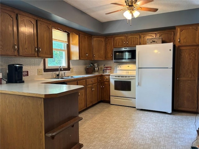 2425 Elephant Trl, Saint Joseph, MO 64506 - kitchen featuring white appliances, brown cabinetry, a ceiling fan, and a peninsula