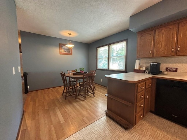 2425 Elephant Trl, Saint Joseph, MO 64506 - kitchen featuring a peninsula, light countertops, a textured ceiling, brown cabinets, and pendant lighting