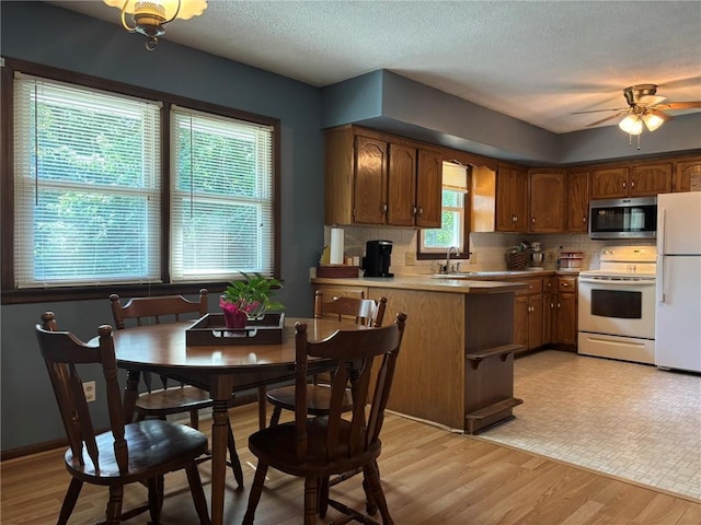 2425 Elephant Trl, Saint Joseph, MO 64506 - kitchen with white appliances, decorative backsplash, a peninsula, ceiling fan, and light wood-type flooring