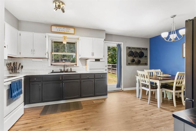800 S Park Ave, Oak Grove, MO 64075 - kitchen featuring white range with electric cooktop, white cabinets, a chandelier, light wood finished floors, and backsplash