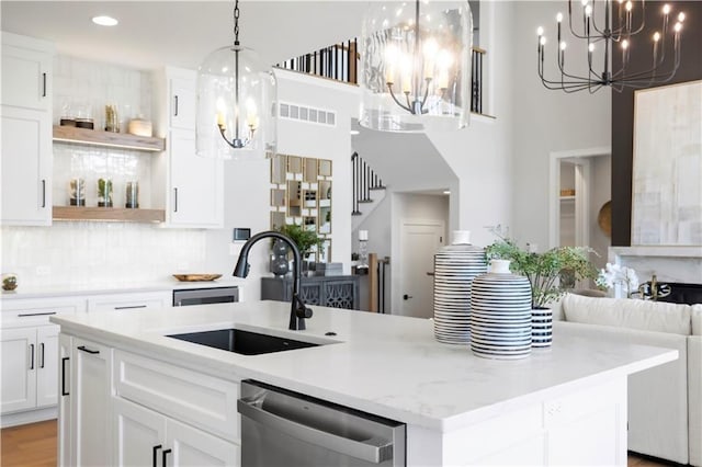 8025 Payne St, Shawnee, KS 66220 - kitchen featuring a chandelier, stainless steel dishwasher, open shelves, an island with sink, and decorative backsplash