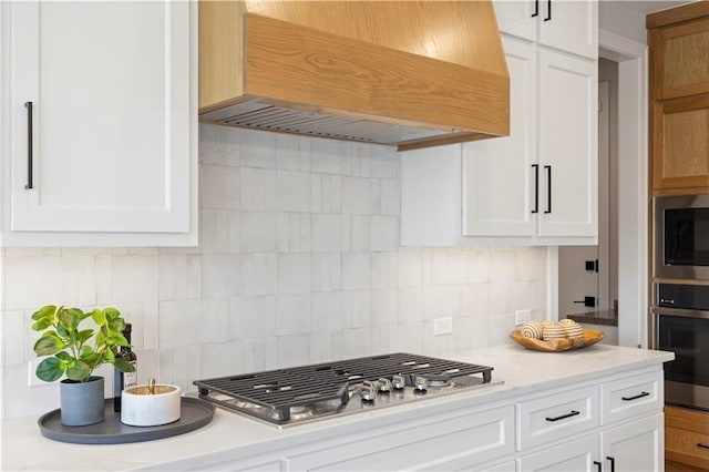 8025 Payne St, Shawnee, KS 66220 - kitchen featuring custom exhaust hood, stainless steel appliances, white cabinets, and decorative backsplash