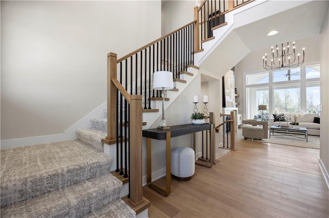8025 Payne St, Shawnee, KS 66220 - staircase featuring a high ceiling, wood finished floors, a chandelier, and recessed lighting
