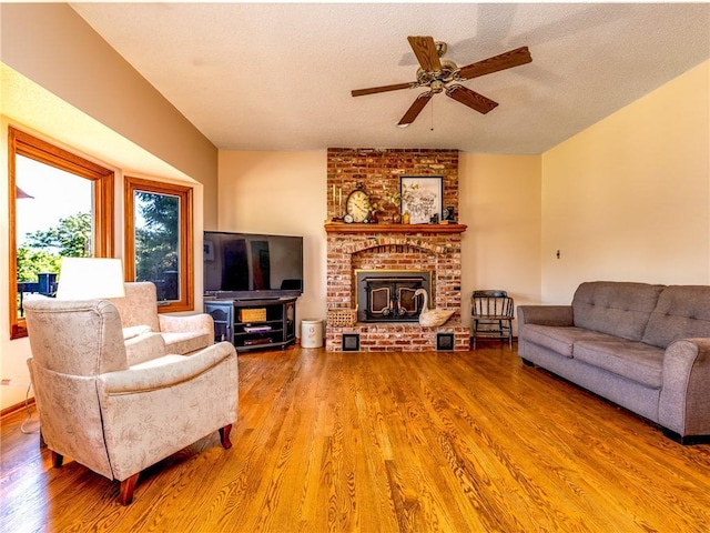 28804 E 116th St, Lees Summit, MO 64086 - living room with wood finished floors, ceiling fan, a brick fireplace, and a textured ceiling