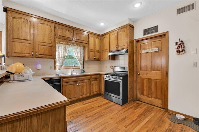 2431 S Ponca Ave, Independence, MO 64057 - kitchen with gas range, under cabinet range hood, dishwasher, brown cabinets, and light countertops
