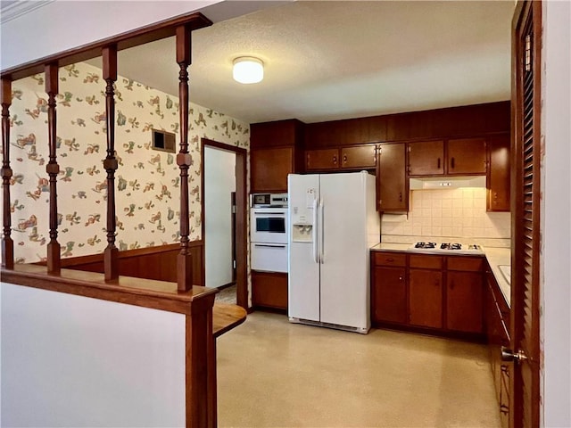 15007 E 41st St, Independence, MO 64055 - kitchen featuring white appliances, wallpapered walls, a warming drawer, under cabinet range hood, and light countertops