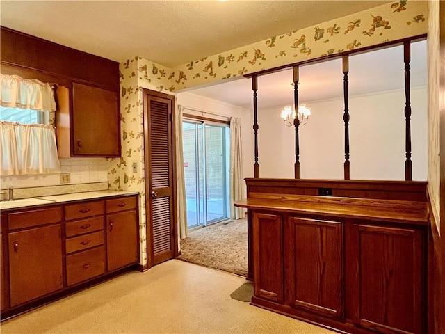 15007 E 41st St, Independence, MO 64055 - kitchen with wallpapered walls, light carpet, light countertops, a chandelier, and brown cabinetry