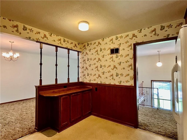 15007 E 41st St, Independence, MO 64055 - hallway featuring a wainscoted wall, light colored carpet, a chandelier, wallpapered walls, and a textured ceiling