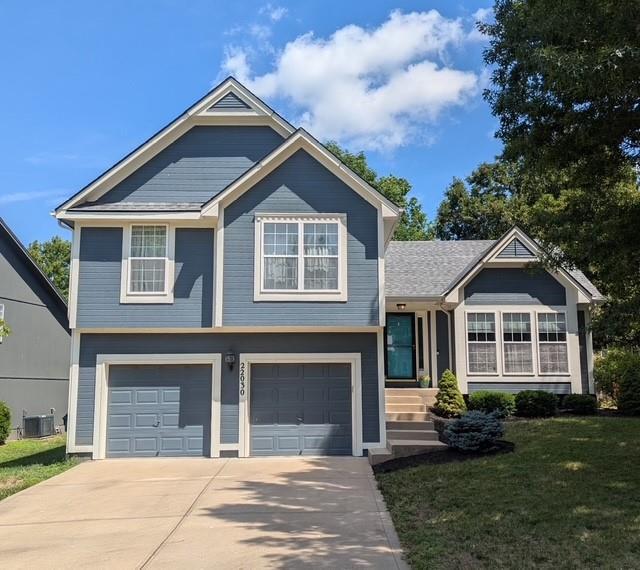 22030 W 51st Ter, Shawnee, KS 66226 - tri-level home featuring a garage, concrete driveway, and a front lawn