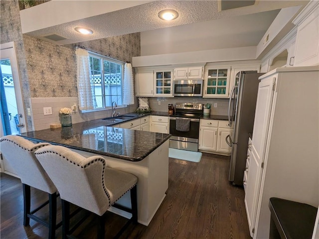 22030 W 51st Ter, Shawnee, KS 66226 - kitchen featuring appliances with stainless steel finishes, a peninsula, dark wood-style flooring, white cabinets, and glass insert cabinets