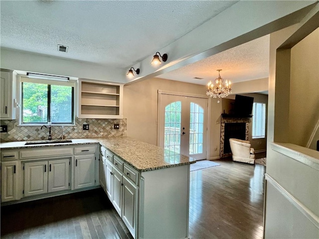2811 Chatelain Ct Unit A, Independence, MO 64057 - kitchen with a textured ceiling, dark wood finished floors, tasteful backsplash, a peninsula, and a chandelier