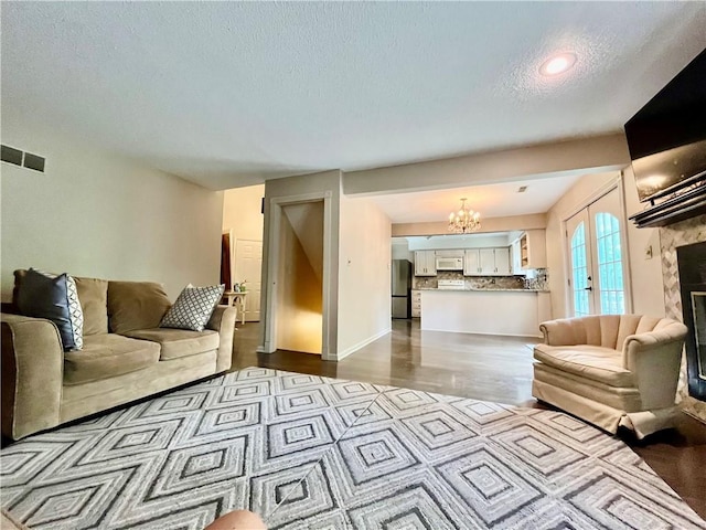 2811 Chatelain Ct Unit A, Independence, MO 64057 - living room featuring a chandelier, a textured ceiling, a tile fireplace, and dark wood-type flooring