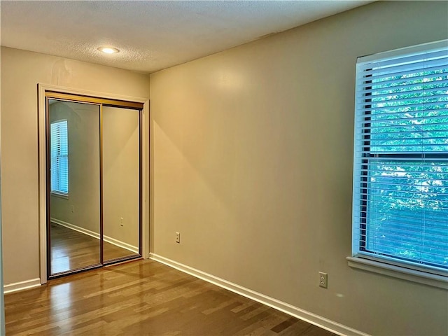 2811 Chatelain Ct Unit A, Independence, MO 64057 - unfurnished bedroom featuring wood finished floors, multiple windows, a closet, and a textured ceiling