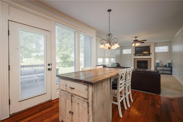3132 SW Damon Ln, Lees Summit, MO 64082 - kitchen featuring wood counters, dark wood-style flooring, a breakfast bar, a glass covered fireplace, and crown molding