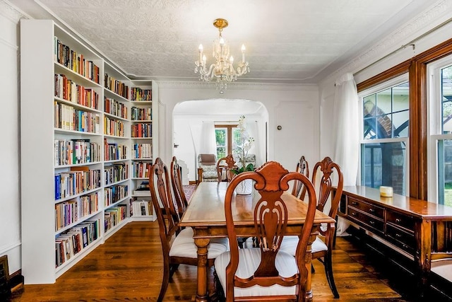 7101 Harrison St, Kansas City, MO 64131 - dining space featuring arched walkways, wood finished floors, a chandelier, built in features, and ornamental molding