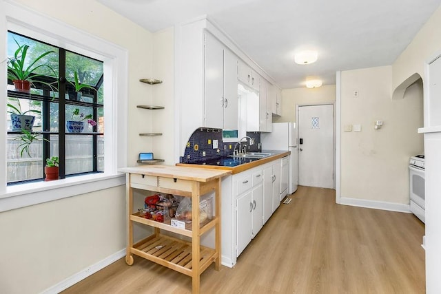 7101 Harrison St, Kansas City, MO 64131 - kitchen with light wood-type flooring, white cabinets, decorative backsplash, and white appliances
