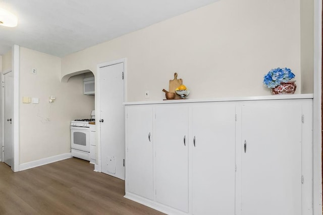 7101 Harrison St, Kansas City, MO 64131 - kitchen with white gas range, wood finished floors, white cabinets, and light countertops