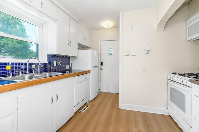 7101 Harrison St, Kansas City, MO 64131 - kitchen with white appliances, light wood finished floors, tasteful backsplash, and white cabinets