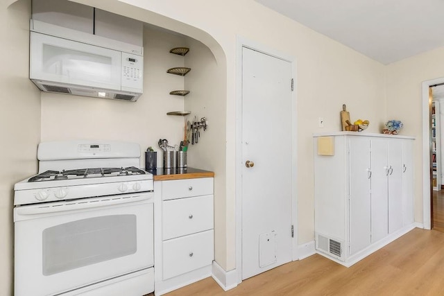 7101 Harrison St, Kansas City, MO 64131 - kitchen with white appliances, light wood-type flooring, white cabinetry, and arched walkways