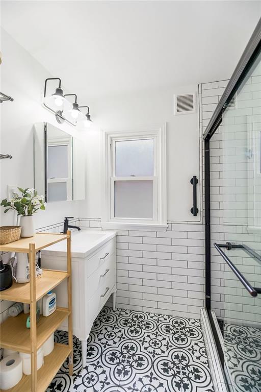 7101 Harrison St, Kansas City, MO 64131 - full bathroom featuring a stall shower, vanity, and tile patterned flooring