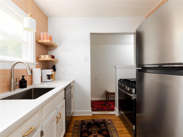 4206 Mission Rd, Kansas City, KS 66103 - kitchen with appliances with stainless steel finishes, light wood-style floors, backsplash, white cabinets, and light countertops