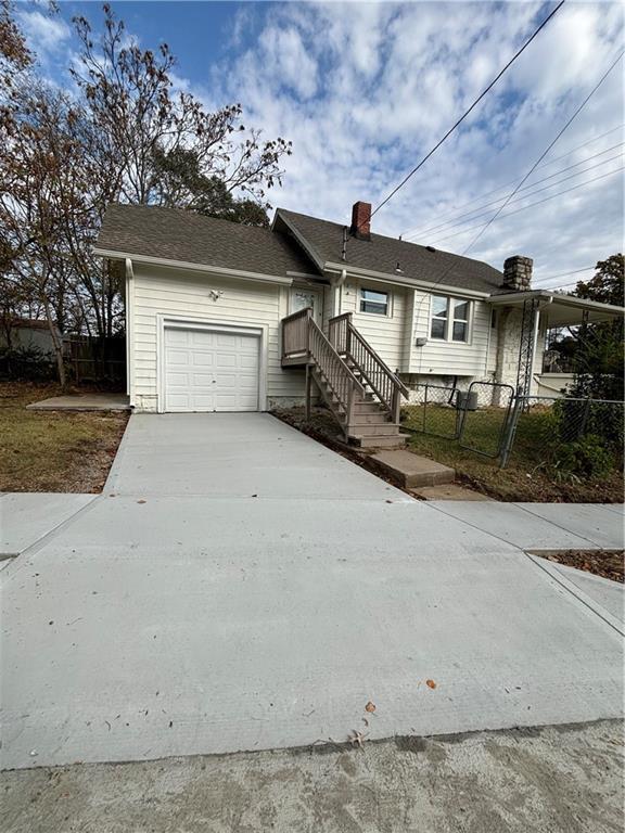 4206 Mission Rd, Kansas City, KS 66103 - ranch-style home featuring concrete driveway, an attached garage, and a chimney