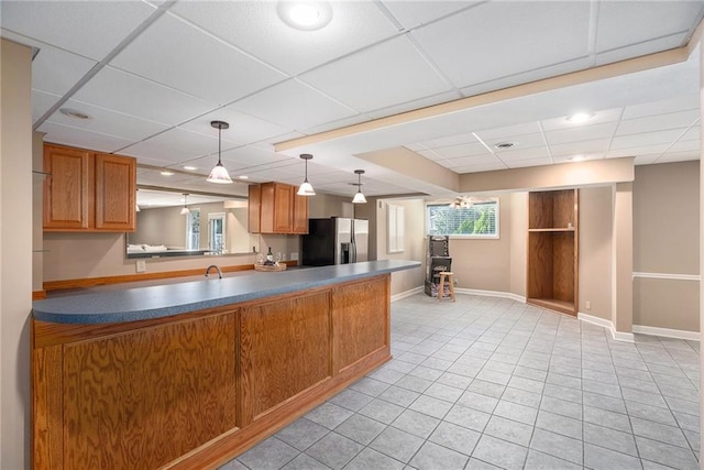 14622 S Garnett St, Olathe, KS 66062 - kitchen featuring stainless steel fridge, a paneled ceiling, brown cabinets, light tile patterned floors, and hanging light fixtures
