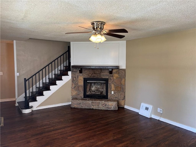 4202 Dr Greaves Rd, Grandview, MO 64030 - unfurnished living room featuring ceiling fan, wood finished floors, stairway, a fireplace, and a textured ceiling