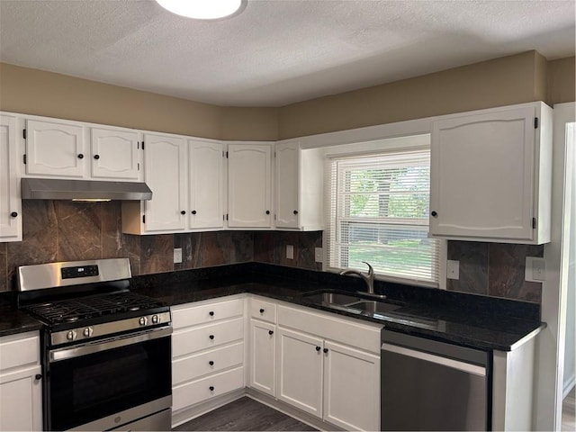 4202 Dr Greaves Rd, Grandview, MO 64030 - kitchen featuring appliances with stainless steel finishes, under cabinet range hood, white cabinetry, tasteful backsplash, and dark wood finished floors