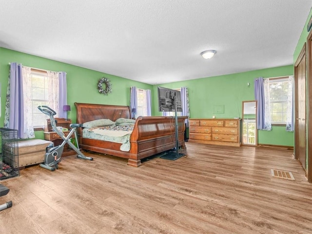 1490 216th St, Lathrop, MO 64465 - bedroom featuring light wood-style floors, multiple windows, and a textured ceiling